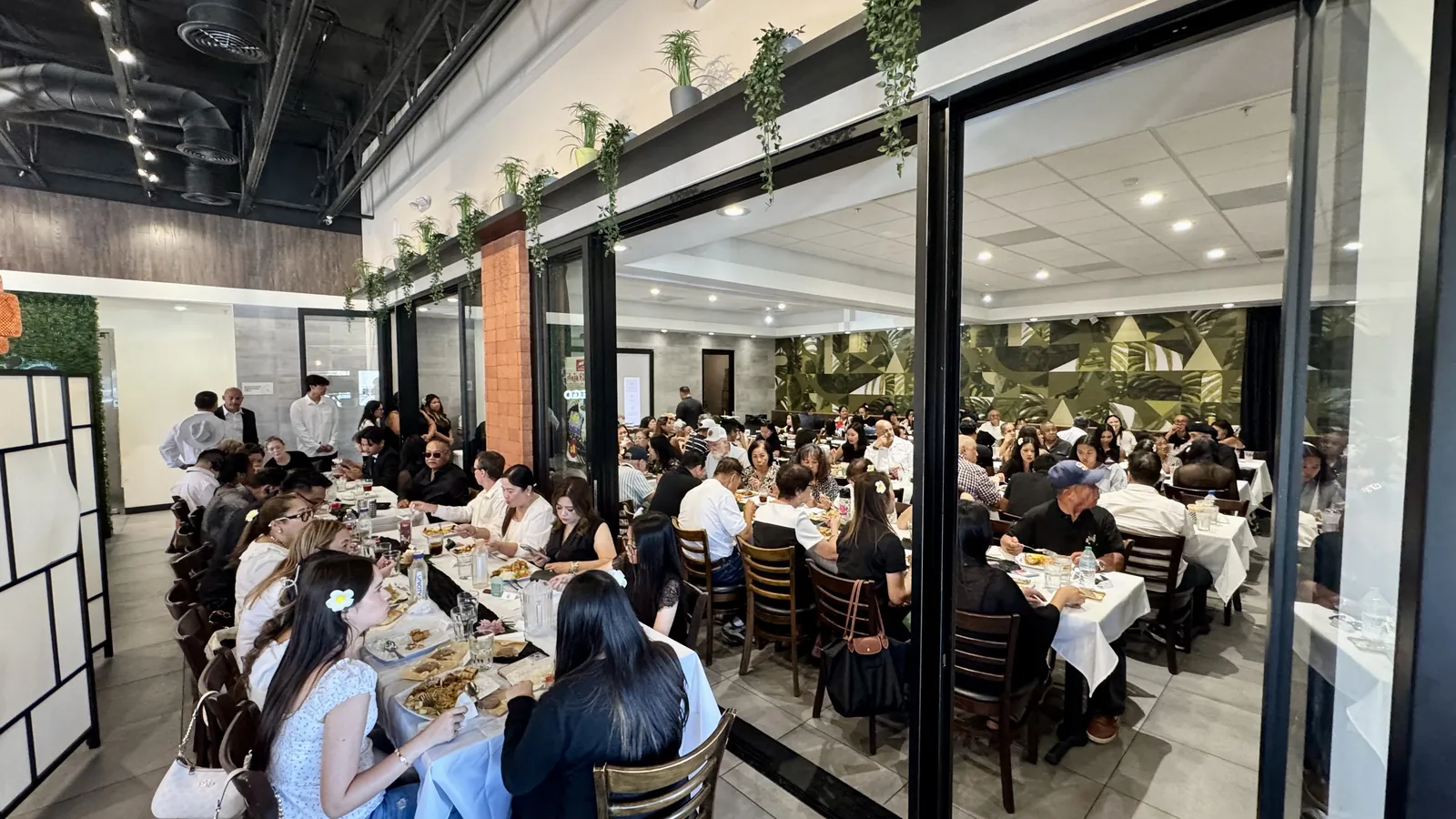 The Max's San Diego dining room set for a large celebration — long tables in white linen, the green leaf mural behind